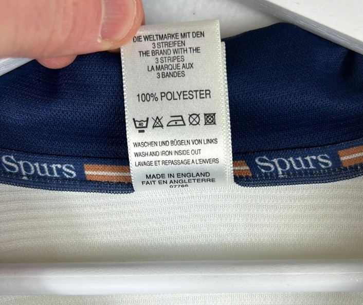 Waslabel van Tottenham Hotspur shirt met 100% polyester en wasinstructies binnenstebuiten wassen